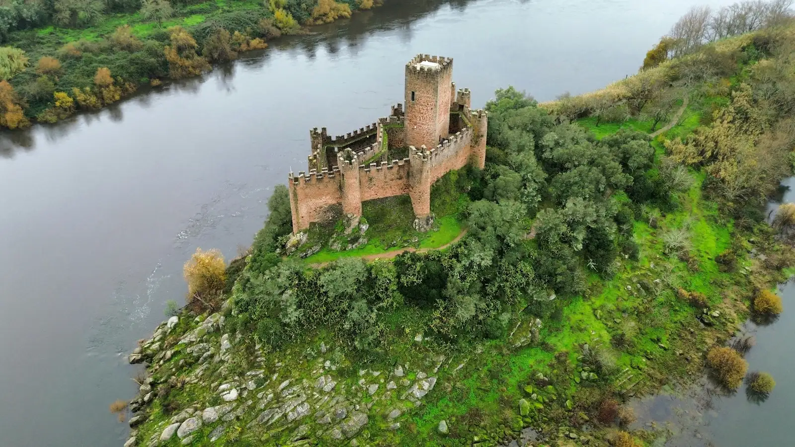 Aerial view of Almourol castle, a small walled fortress with a square keep, on a wooded rocky island in the Tagus river, central Portugal