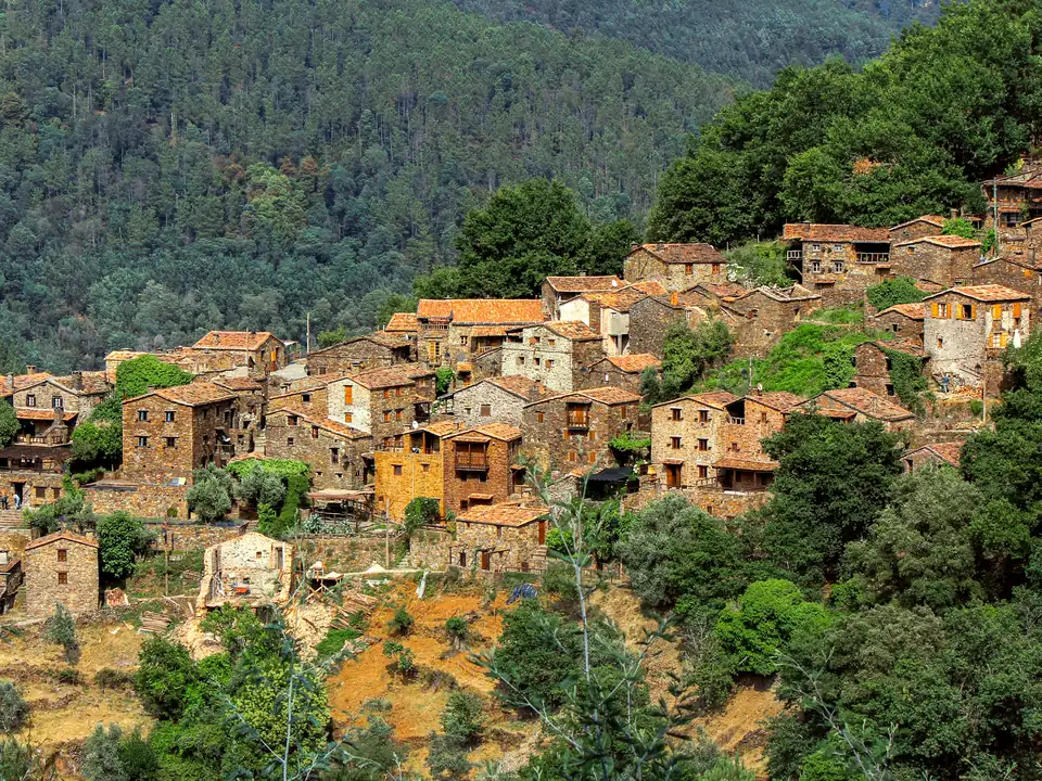 Stone houses of the schist village of Talasnal stacked on a wooded hillside in the Serra da Lousã